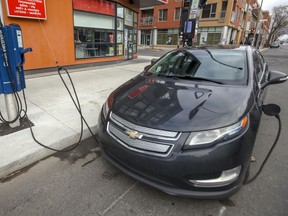 An electric car is connected to a roadside charging station in Montreal.
